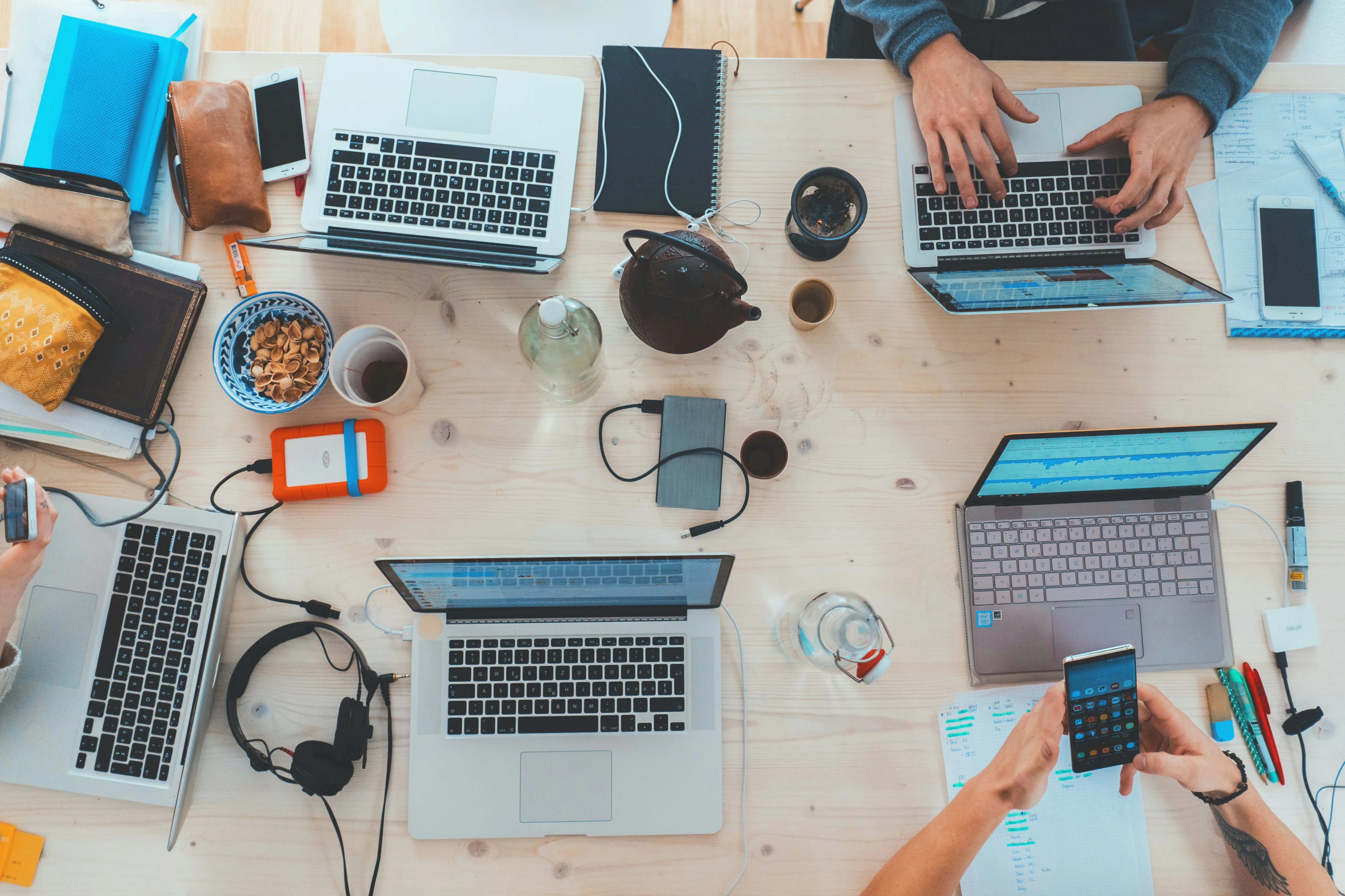 Top view of team workspace with laptops, smartphones, and notes.