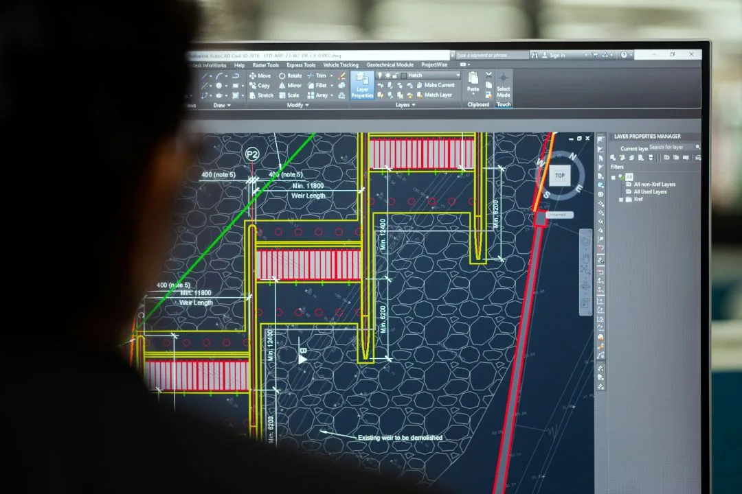 Person viewing a technical construction plan on a computer screen.