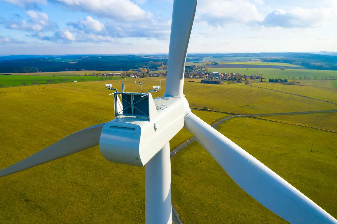 Nahaufnahme einer Windkraftanlage über ländlicher Landschaft