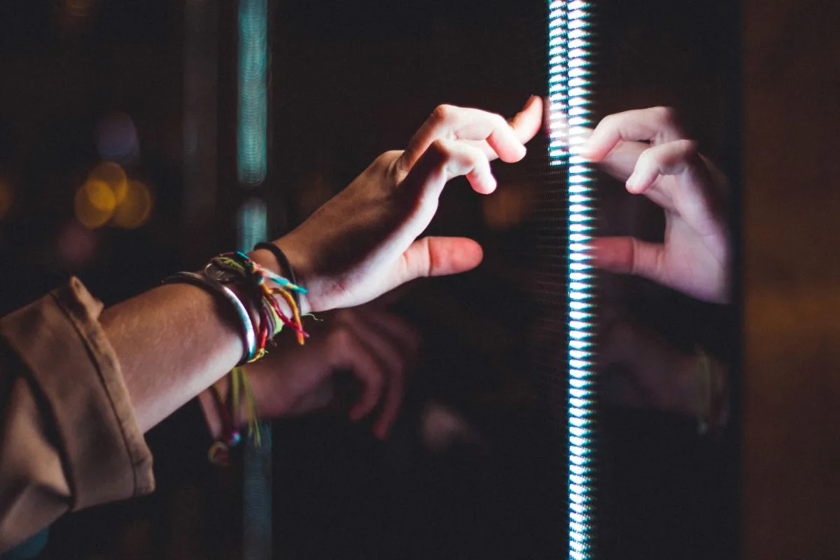 Hands touching an interactive light installation – digital innovation and experimentation.