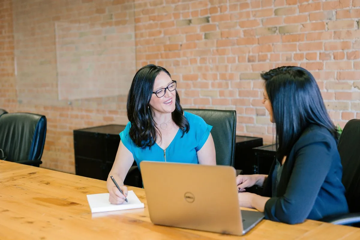 Two women are having a meeting, with a laptop on the table, research allowance.