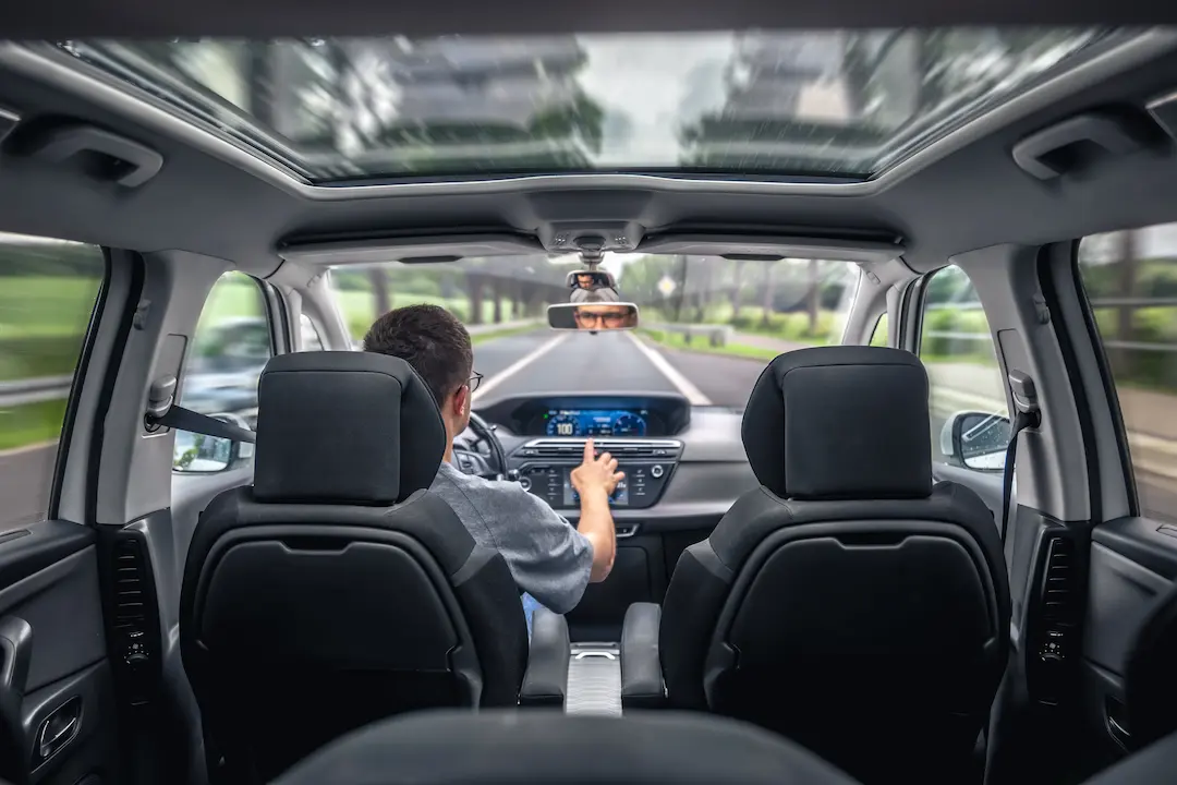 Fahrer im Auto mit Blick auf Straße und Panorama-Glasdach