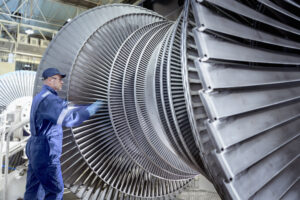 Engineer inspecting and maintaining a low-pressure steam turbine in a power plant